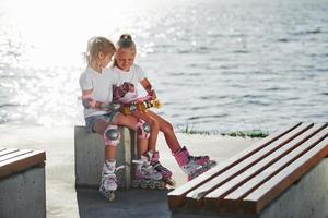 duas meninas com patins ao ar livre perto do lago ao fundo foto