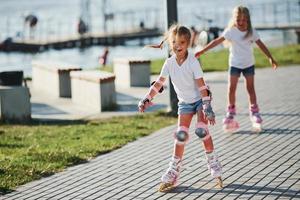 dois lindos filhos andando de patins no parque durante o dia foto