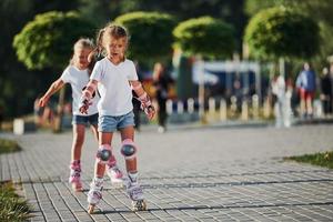dois lindos filhos andando de patins no parque durante o dia foto