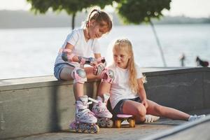 conversando entre si. na rampa para esportes radicais. duas meninas com patins ao ar livre se divertem foto