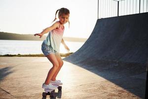 primeiras tentativas. dia ensolarado. garoto se divertir com o skate na rampa. garotinha alegre foto