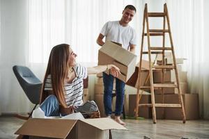 hora de desempacotar essas caixas. casal jovem alegre em seu novo apartamento. concepção de movimento foto