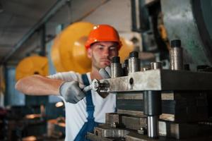 usando chave inglesa. homem de uniforme trabalha na produção. tecnologia industrial moderna foto