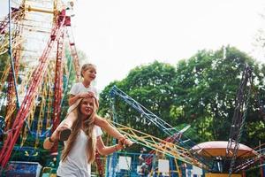 menina alegre sua mãe se diverte no parque juntos perto de atrações foto