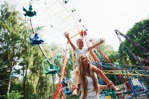 menina alegre sua mãe se diverte no parque juntos perto de atrações foto