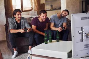 grupo de amigos se diverte jogando jogo de console dentro de casa na sala de estar foto