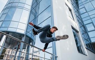 jovem fazendo parkour na cidade durante o dia. concepção de esportes radicais foto