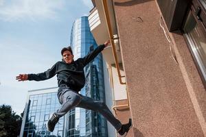 jovem fazendo parkour na cidade durante o dia. concepção de esportes radicais foto