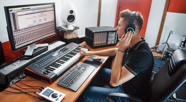 engenheiro de som em fones de ouvido trabalhando e mixando música dentro de casa no estúdio foto