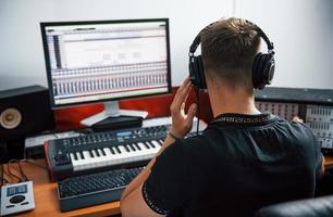 engenheiro de som em fones de ouvido trabalhando e mixando música dentro de casa no estúdio foto