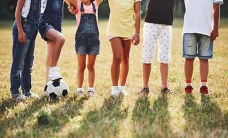 visão de partícula de crianças esportivas com bola de futebol fica juntos no campo em dia ensolarado foto