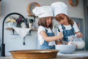 filhos de família em uniforme de chef branco preparando comida na cozinha foto