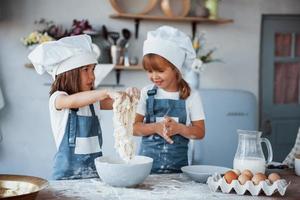 filhos de família em uniforme de chef branco preparando comida na cozinha foto