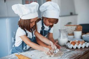 concentrando-se em cozinhar. filhos de família em uniforme de chef branco preparando comida na cozinha foto