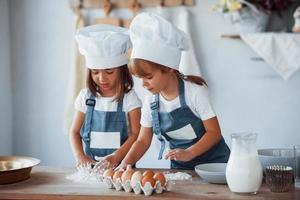 filhos de família em uniforme de chef branco preparando comida na cozinha foto