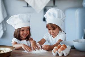 concentrando-se em cozinhar. filhos de família em uniforme de chef branco preparando comida na cozinha foto