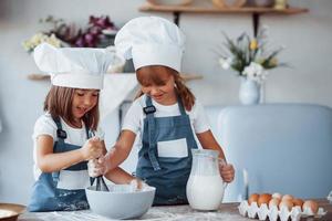 filhos de família em uniforme de chef branco preparando comida na cozinha foto