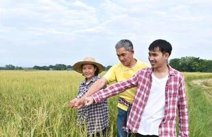 retrato homem idoso asiático na camisa amarela está anotando informações de plantio, perguntando e entrevistando jovem asiático e agricultora nas proximidades, foco suave e seletivo. foto