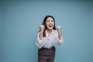 uma jovem mulher asiática com uma expressão de sucesso feliz vestindo camisa branca isolada por fundo azul foto