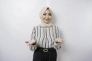 jovem mulher asiática vestindo um hijab apresentando uma ideia enquanto olha sorrindo no fundo branco isolado foto
