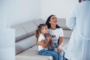 mãe com sua filha fofa está visitando a clínica. ouvindo o médico foto