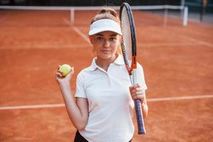 retrato de jovem tenista em roupas esportivas está na quadra ao ar livre foto