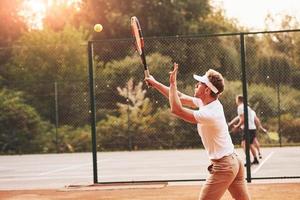 jovem tenista em roupas esportivas está na quadra ao ar livre foto
