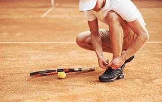 se preparando. jovem tenista em roupas esportivas está na quadra ao ar livre foto