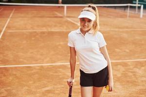 retrato de jovem tenista em roupas esportivas está na quadra ao ar livre foto