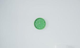 foto minimalista do relógio verde moderno que está pendurado na parede branca
