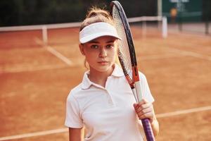 retrato de jovem tenista em roupas esportivas está na quadra ao ar livre foto