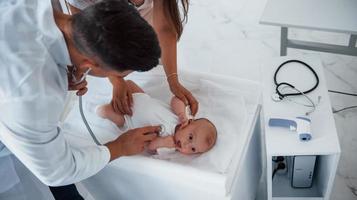 jovem pediatra está com bebê na clínica durante o dia foto