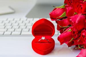 caixa de presente com anel de diamante e rosas vermelhas na mesa de trabalho para surpreender no noivado no dia dos namorados. foto