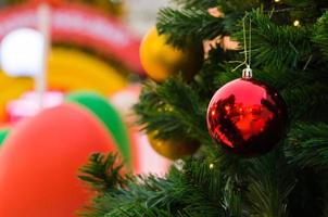 bugiganga vermelha e outro ornamento pendurado na árvore de natal com fundo colorido. foto