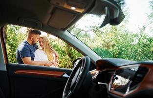 interior do veículo. casal se abraçando na floresta perto de carro moderno foto