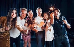 grupo de amigos alegres comemorando o ano novo dentro de casa com bebidas nas mãos foto