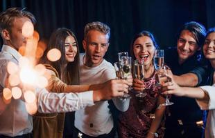 grupo de amigos alegres comemorando o ano novo dentro de casa com bebidas nas mãos foto