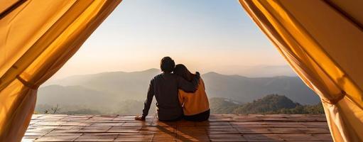 jovem casal viajante olhando bela paisagem ao pôr do sol e acampar na montanha, conceito de estilo de vida de viagens de aventura foto
