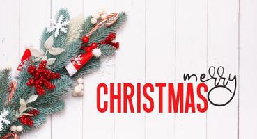texto de feliz natal com composição de natal feita de pinheiro, flocos de neve e vista superior de decorações festivas foto