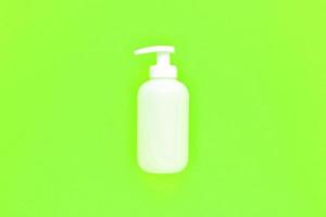 garrafa de bomba dispensadora de plástico sem marca branca em fundo verde neon claro com espaço de cópia. maquete de embalagem cosmética, frasco de sabonete líquido, desinfetante para as mãos sem rótulo, shampoo spa orgânico, gel de banho foto