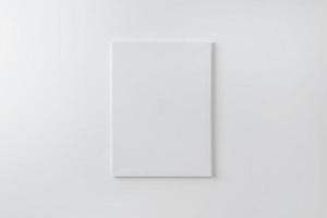 tela de arte vertical em branco na parede. superfície limpa para maquete, apresentação de arte. luz suave na parede branca foto