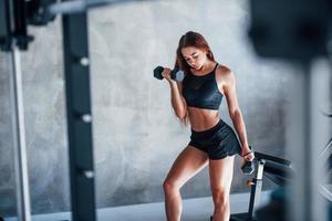 mulher jovem fitness está no ginásio com halteres nas mãos foto