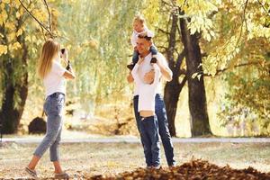 família jovem e alegre dá um passeio juntos em um parque de outono foto