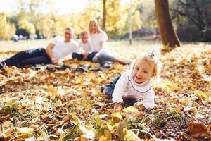 família jovem alegre deitada no chão e descansar em um parque de outono juntos foto