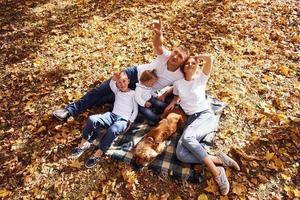 vista superior da jovem família alegre que descansa em um parque de outono juntos foto