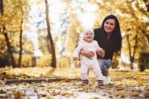 mãe em roupas casuais com seu filho está no lindo parque outono foto