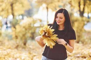 retrato de morena que se diverte com folhas no belo parque outono foto