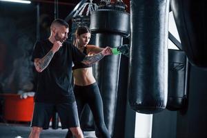 jovem treinador de boxe tatuado ensina jovem no ginásio foto