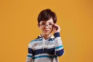 retrato de jovem estudante inteligente no estúdio contra fundo amarelo foto