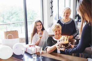 mulher sênior com família e amigos comemorando um aniversário dentro de casa foto